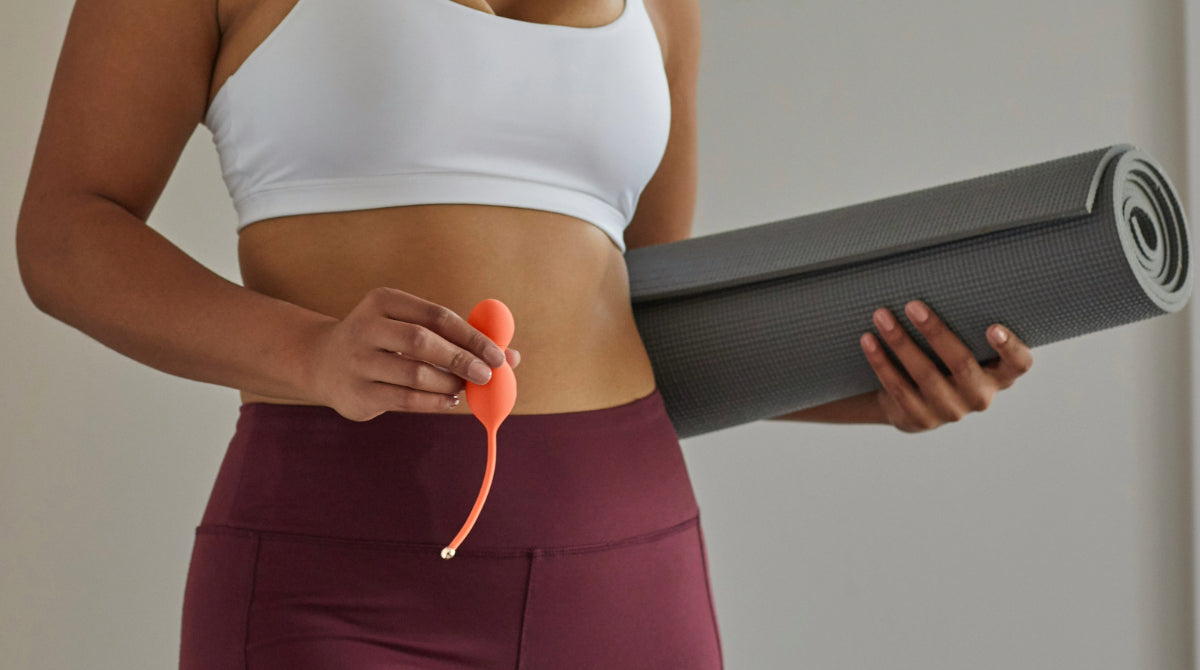 woman holding kegel balls and a yoga mat